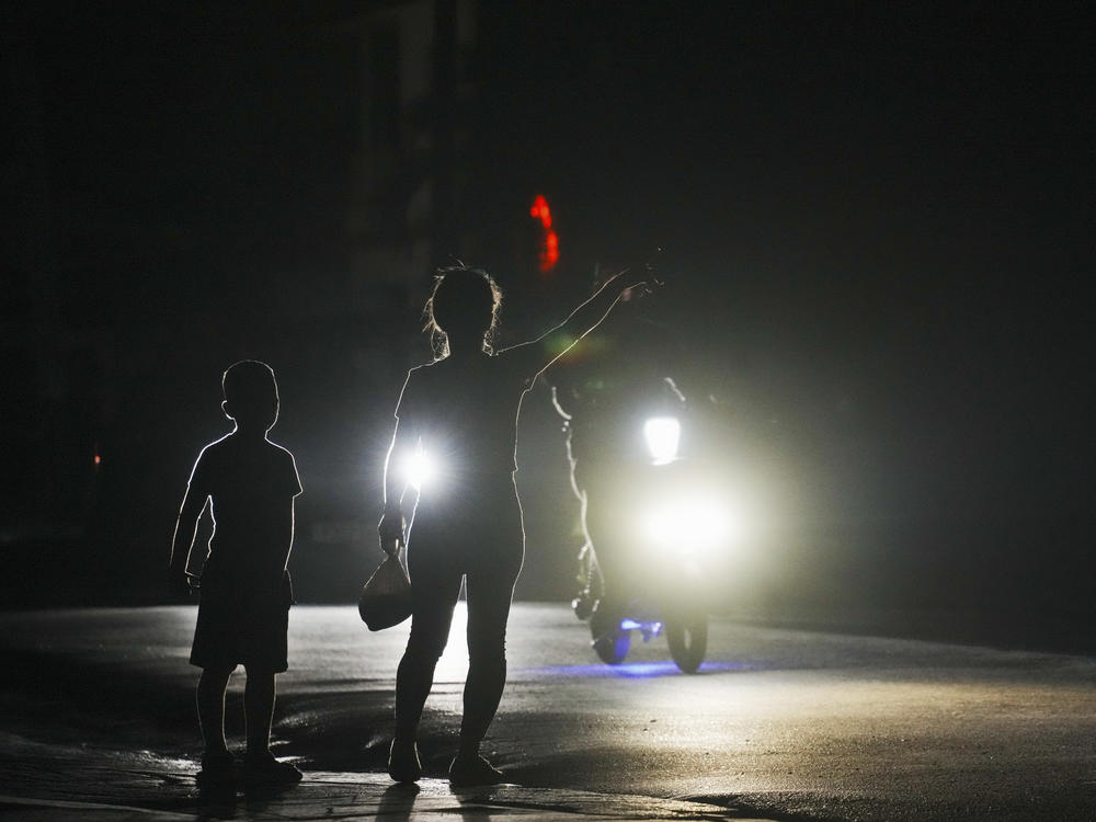 A woman and a boy attempt to hitch a ride during a scheduled power outage in Bauta, Cuba, Monday. The island is facing an energy crisis, with waves of blackouts worsening in recent weeks.