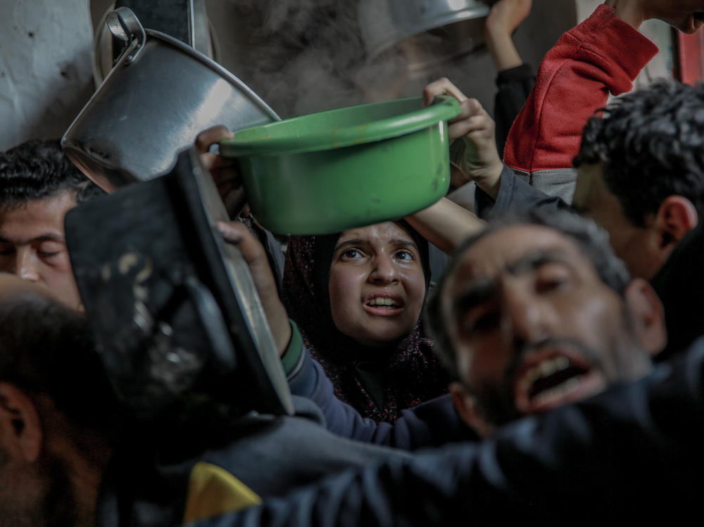 Palestinians gather to collect aid food in Beit Lahia, in the northern Gaza Strip, on February 26, 2024.