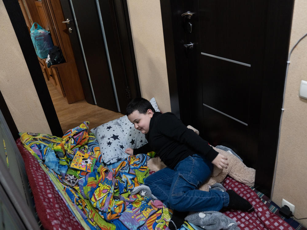 Maksym lies on a mattress in the hallway of his home while an air raid siren sounds in Kharkiv. It's the only part of the apartment without any windows and he feels safer during the frequent Russian missile attacks.