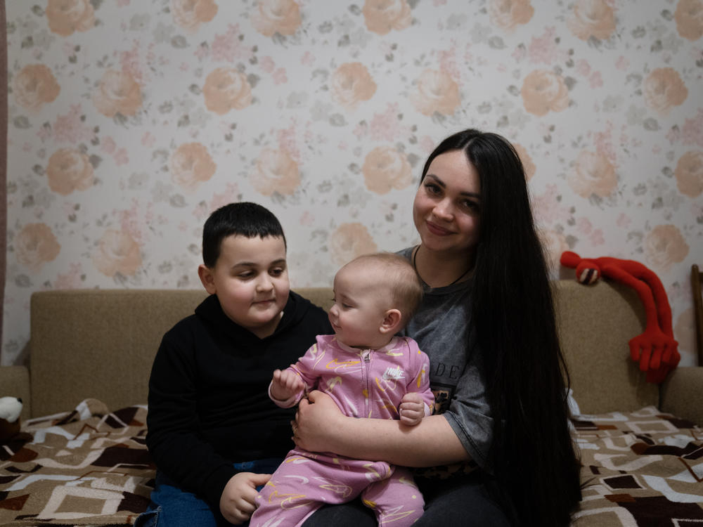 Maksym sits with his mother, Anna Timchenko, and his baby sister, Sonia, at their home.