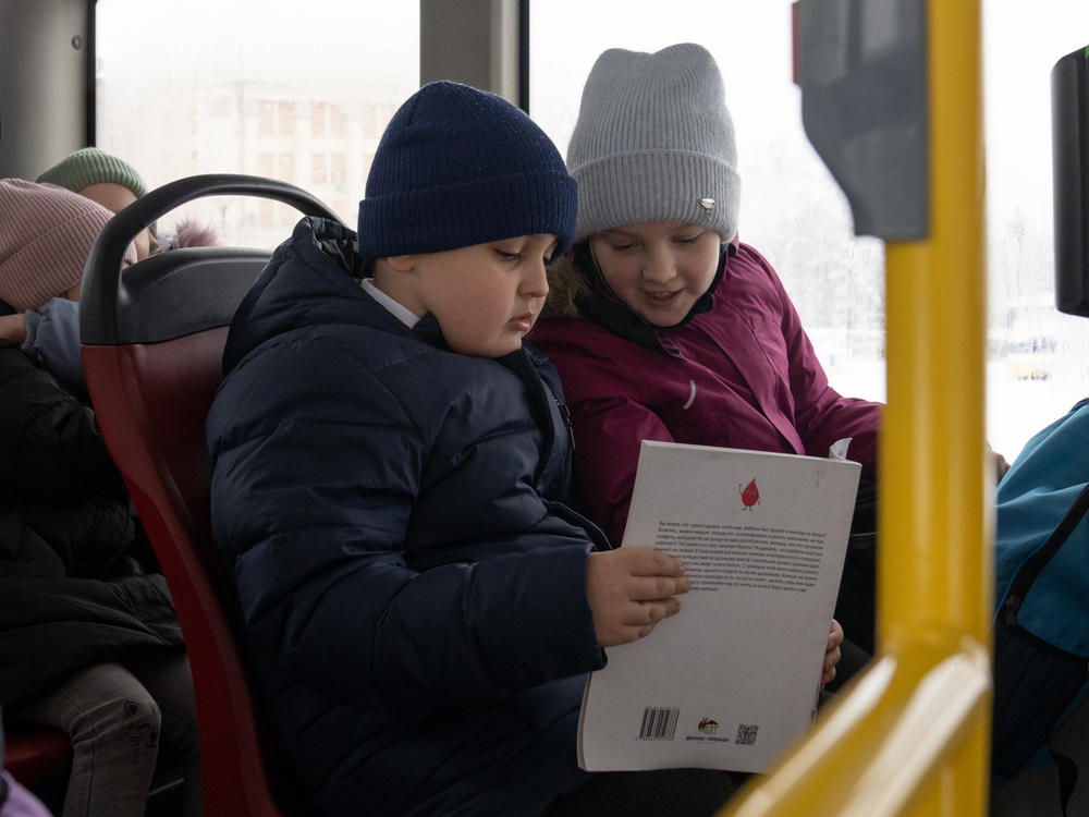 Maksym and his best friend, Kseniia, read a book on the bus while they head home from school.