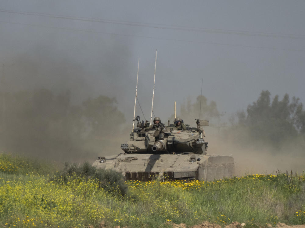 Israeli soldiers move on the top of a tank near the Israeli-Gaza border, as seen from southern Israel, on Thursday.