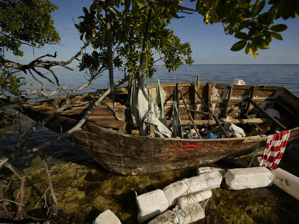 A wooden migrant boat lies grounded on a reef alongside mangroves, at Harry Harris Park in Tavernier, Fla., last year. The U.S. Coast Guard says that since October, has it intercepted and returned about <a href=