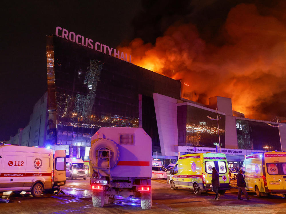 Vehicles of Russian emergency services are parked near the burning Crocus City Hall concert venue, following a reported shooting incident, outside Moscow on Friday.