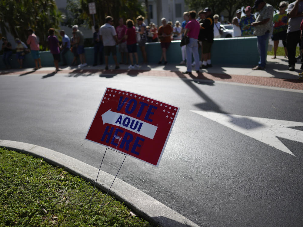 A sign tells voters in English and Spanish where to vote as Lee County voters wait in line to cast their ballots at Northeast Regional Library in Cape Coral, Fla., on Election Day, Tuesday, Nov. 8, 2022.