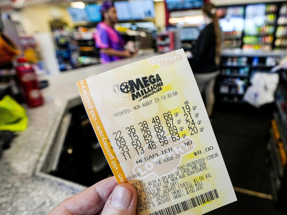A Mega Millions ticket is seen as a person makes a purchase inside a convenience store, Aug. 7, 2023, in Kennesaw, Ga.
