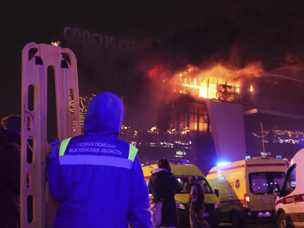 A medic stands near ambulances parked outside the burning building Friday.