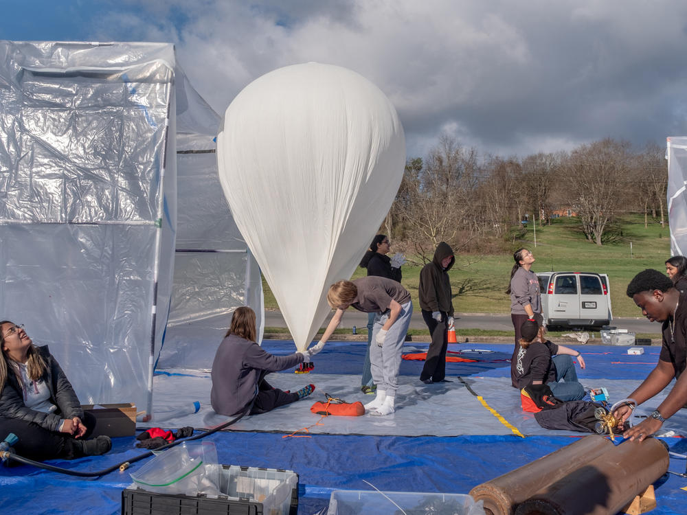 Student volunteers prepare a balloon for a morning launch in Cumberland, Md. On April 8, eclipse day, hundreds of balloons will be launched into the path of the eclipse to study the atmosphere.