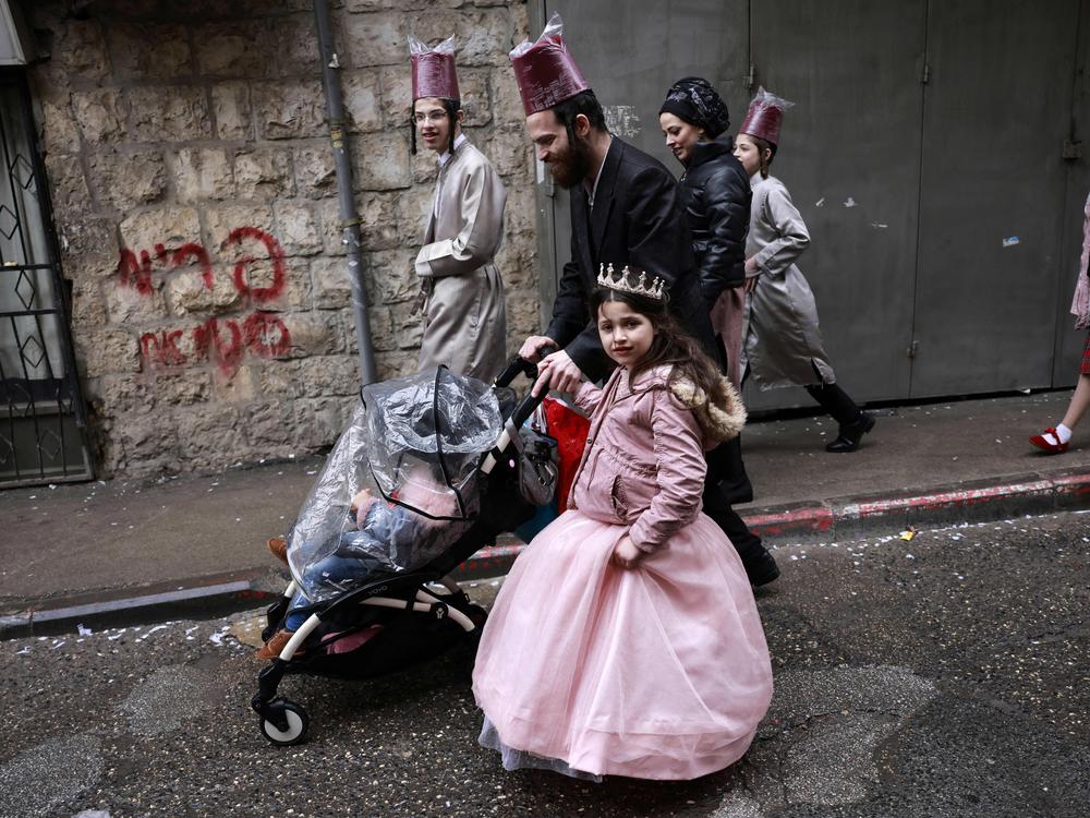 Jewish men and children in Purim costumes celebrate in the Mea Shearim ultra-Orthodox neighbourhood in Jerusalem, on March 18, 2022. The Purim holiday is celebrated with parades and costume parties to commemorate the deliverance of the Jewish people from a plot to exterminate them in the ancient Persian empire 2,500 years ago, as recorded in the Biblical Book of Esther.