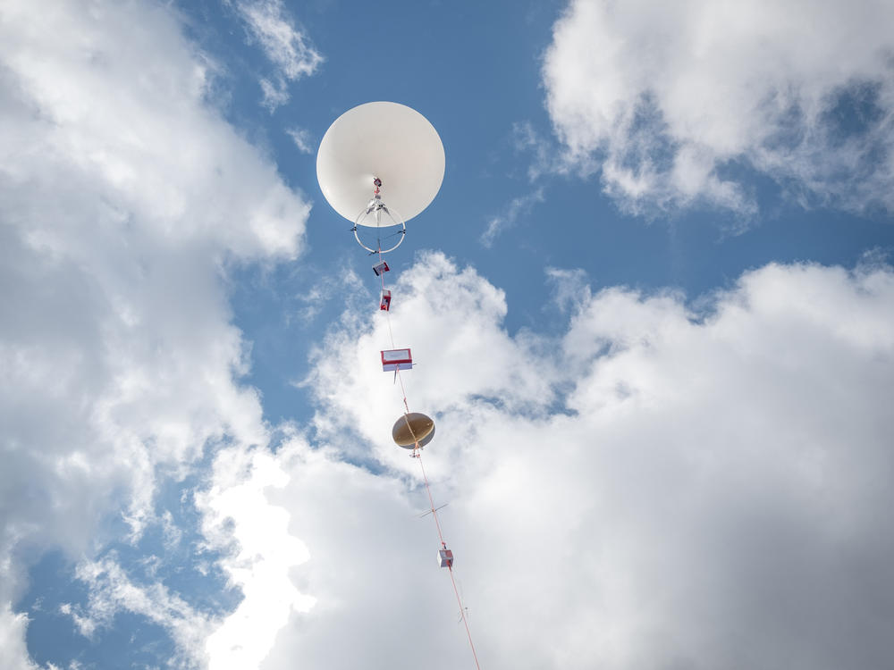 A balloon floats skyward with scientific equipment in tow. On eclipse day dozens of teams will launch hundreds of balloons to study the atmosphere.