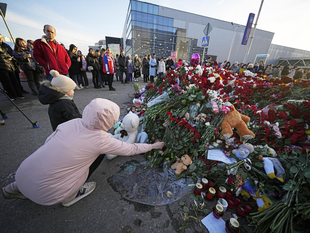 People lay flowers at a makeshift memorial in front of the Crocus City Hall outside Moscow, on Monday. There were calls Monday for harsh punishment for those behind the attack on the Russian concert hall that killed more than 130 people, as authorities combed the burnt-out ruins of the shopping and entertainment complex in search of more bodies.