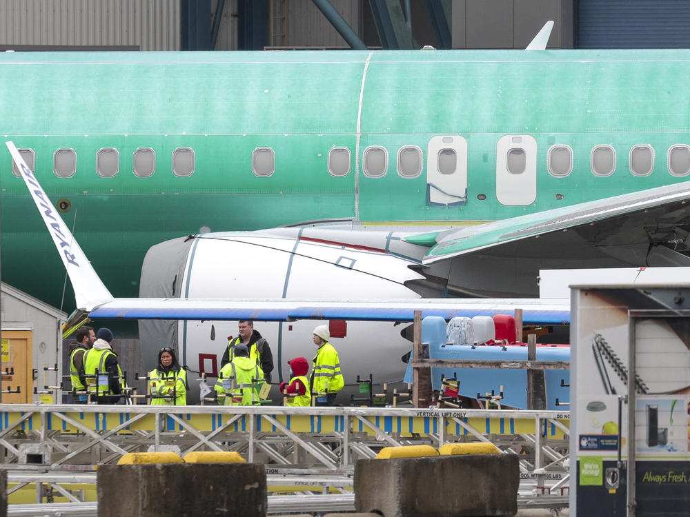 Workers are pictured next to an unpainted 737 aircraft and unattached wing with the Ryanair logo as Boeing's 737 factory teams held a 