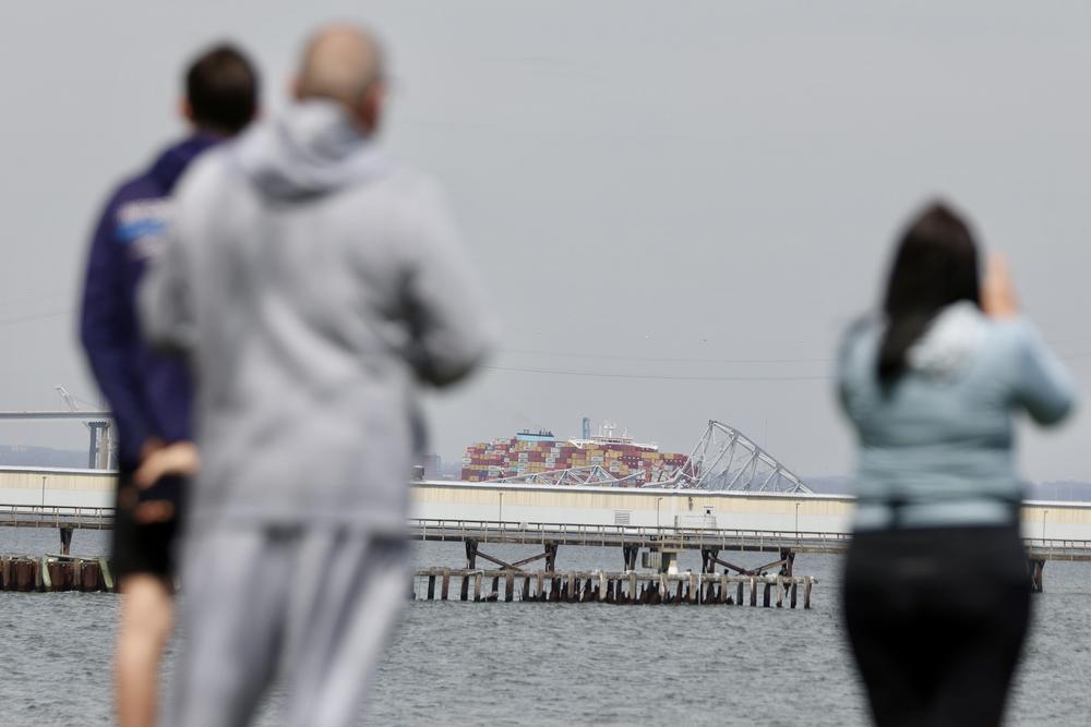 People in Orchard Beach look at the Dali container ship and collapsed Francis Scott Key bridge.
