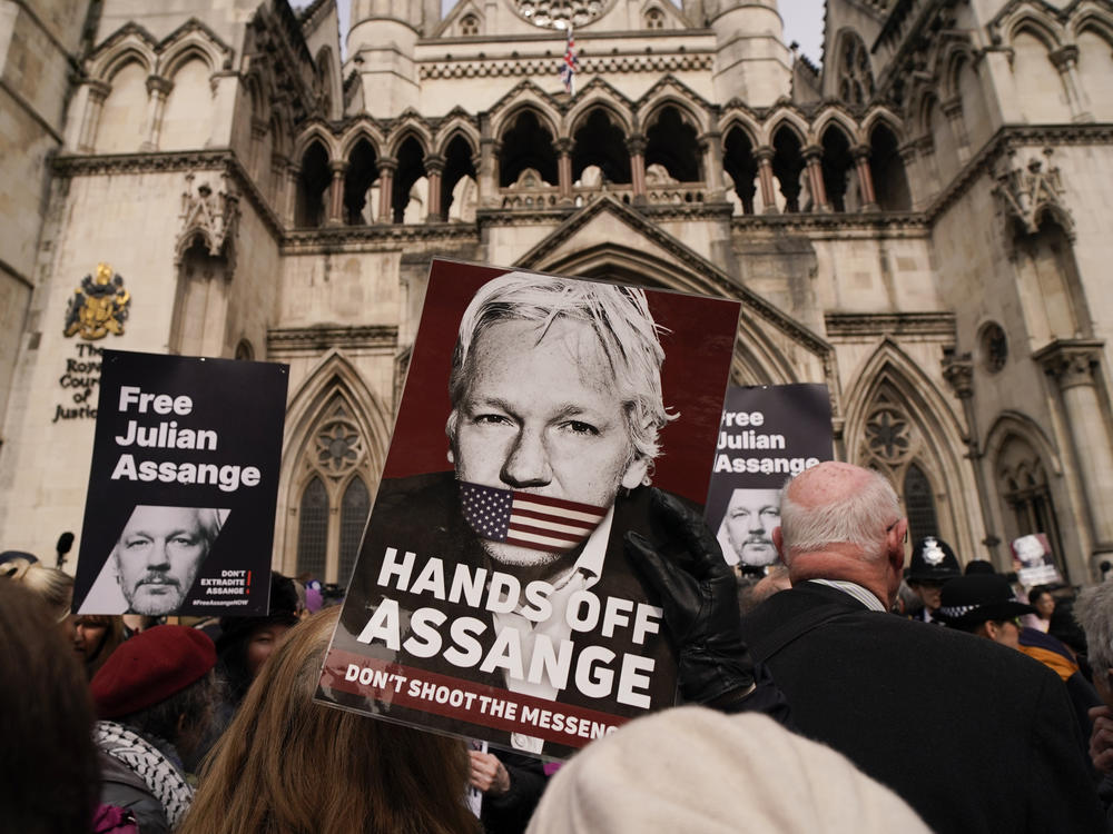 A demonstrator holds a placard, after Stella Assange, wife of WikiLeaks founder Julian Assange, released a statement outside the Royal Courts of Justice, in London, Tuesday.