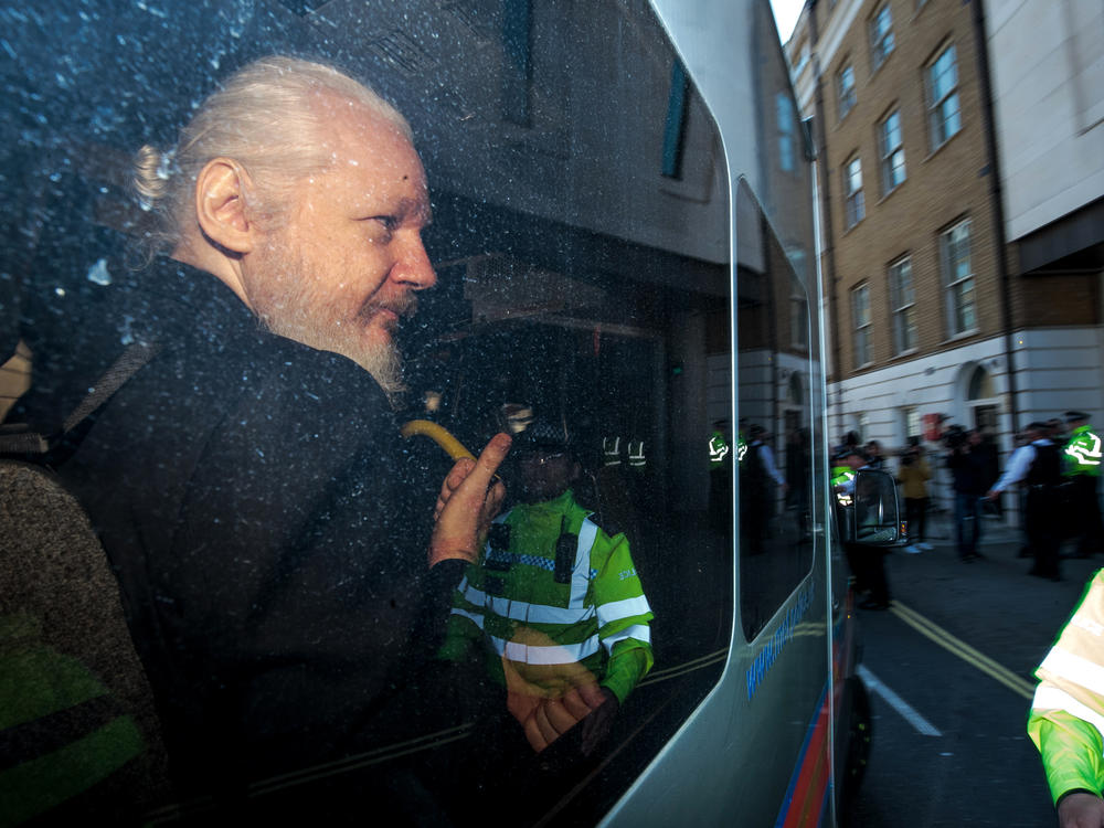 Julian Assange gestures to the media from a police vehicle on his arrival at Westminster Magistrates' Court on April 11, 2019, in London.