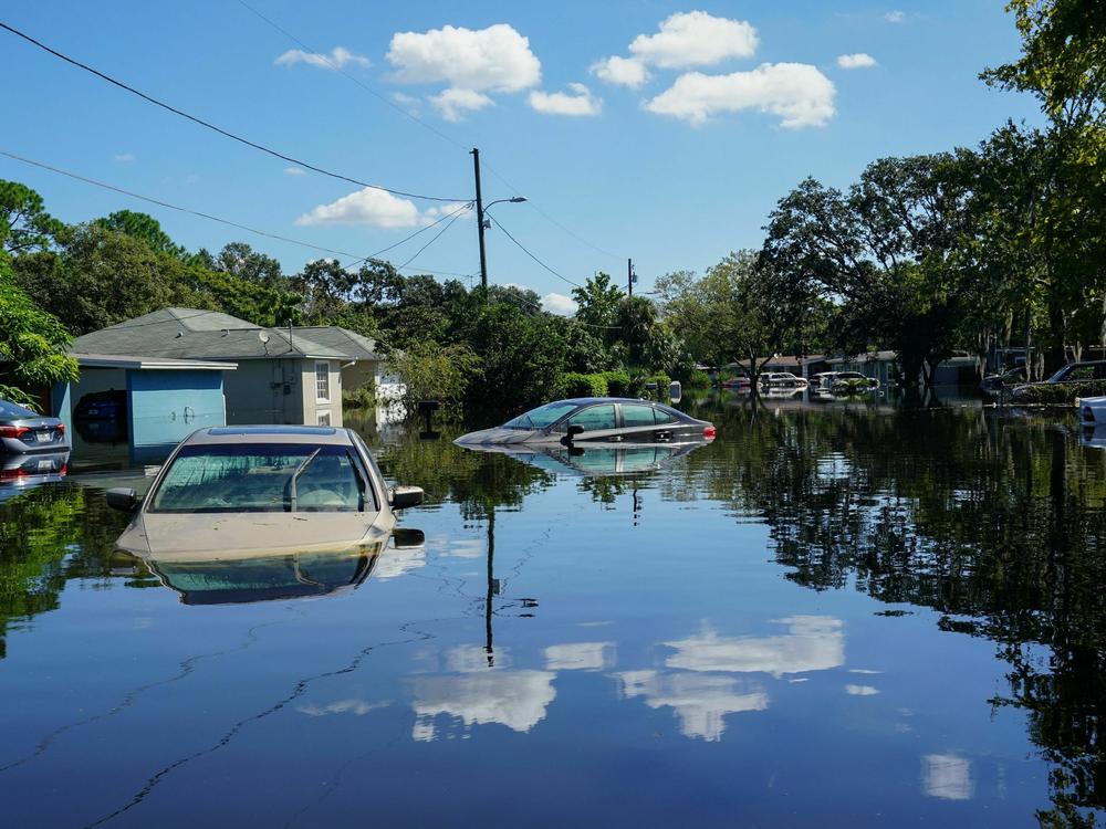 Clouds are reflected on a flooded street with submerged cars in the Orlovista neighborhood following Hurricane Ian on October 1, 2022 in Orlando, Florida.