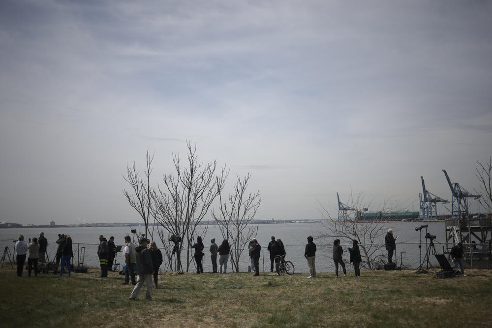Local residents gather to view a cargo ship that ran into and collapsed the Francis Scott Key Bridge in Baltimore, Md.