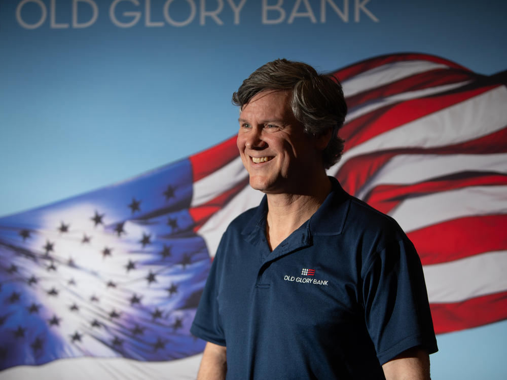 Eric Ohlhausen, chief strategy officer at Old Glory Bank, stands in front of his company's sign at the RePlatform conference.