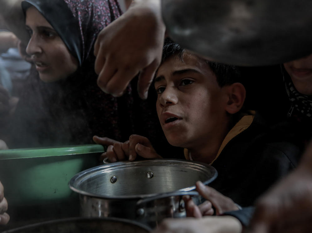 A Palestinian boy waits with his pot among a crowd in Beit Lahia, in northern Gaza, while trying to get a small amount of soup from one of the few soup kitchens, on Feb. 26.
