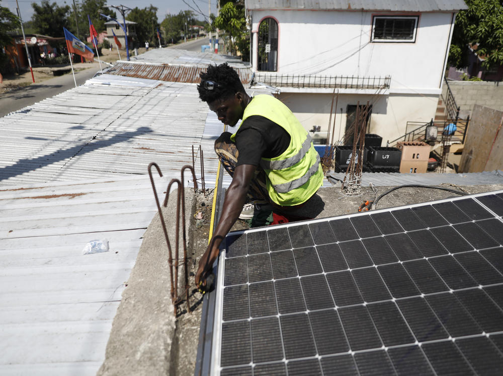 Rod Augustin, measures dimensions for solar panel installation at a local bar in Limonade, Haiti, on March 17, 2024.
