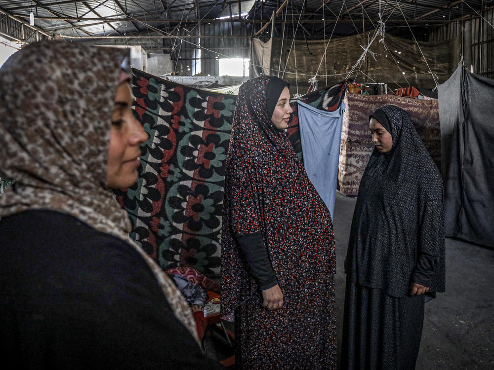 A pregnant Palestinian woman (center) displaced from northern Gaza stands in a warehouse in Rafah, where she is taking shelter, on Feb. 29. About 5,000 women in Gaza are expected to give birth in the next month.