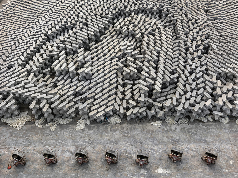 A tetrapod factory in Dongying, China. These concrete blocks are dropped into the ocean to create a barrier that protects low-lying oil refineries from rising sea levels. According to a recent <a href=