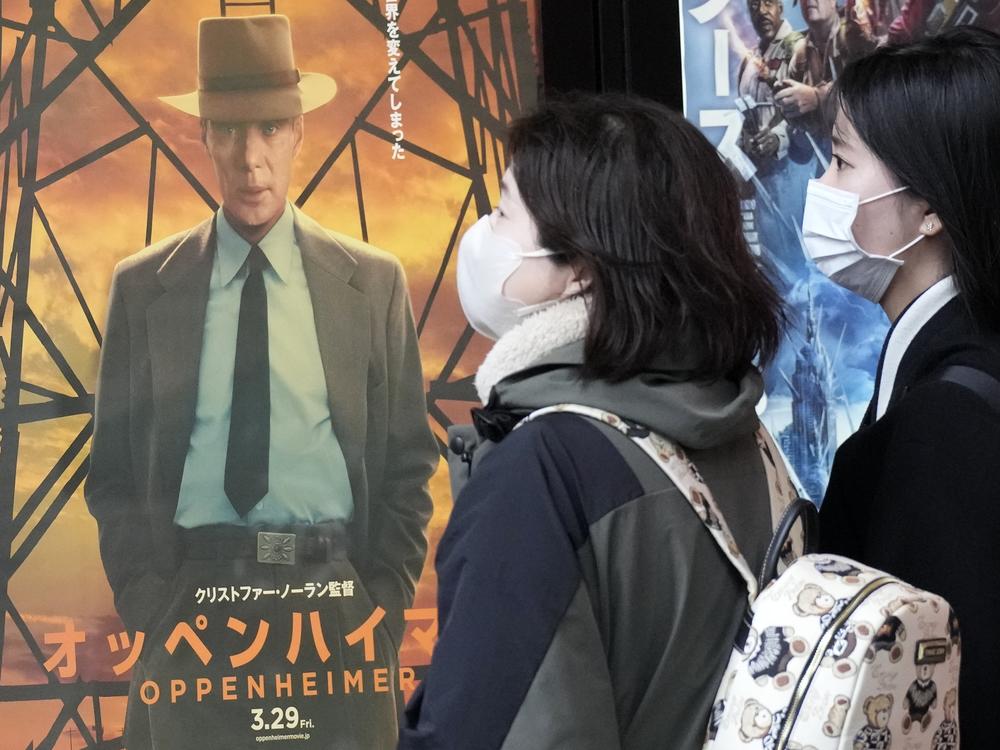 People walk by a poster to promote the movie <em>Oppenheimer</em> on Friday in Tokyo.