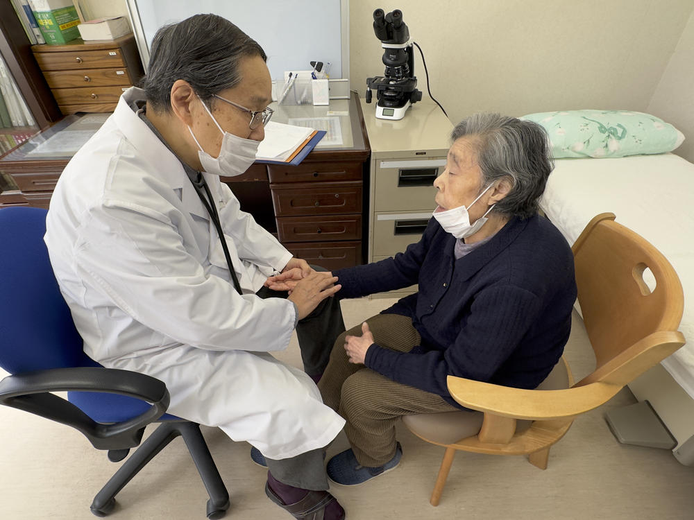 Dr. Masao Tomonaga takes the pulse of an atomic bomb survivor at a care home in Nagasaki, Japan.