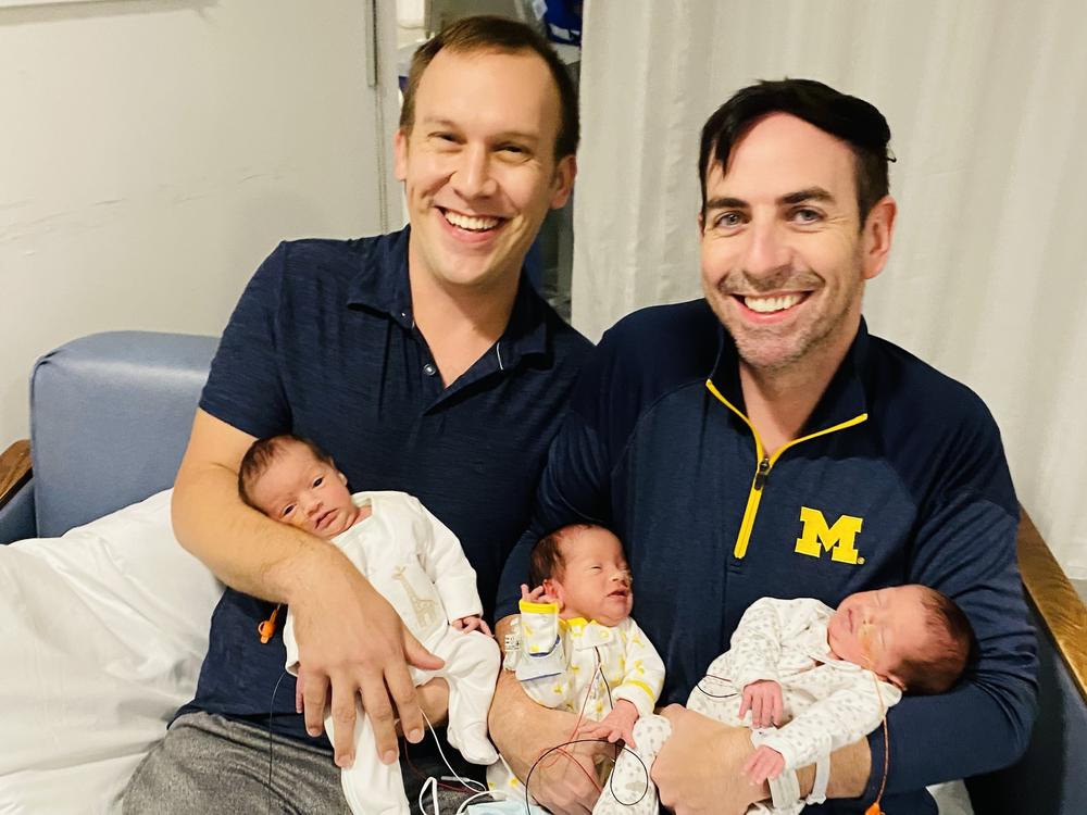 Eric Portenga and Kevin O'Neill hold their newborn triplets (from left) Parker, Robin and Sylvie O'Neill, in Sept. 2021.
