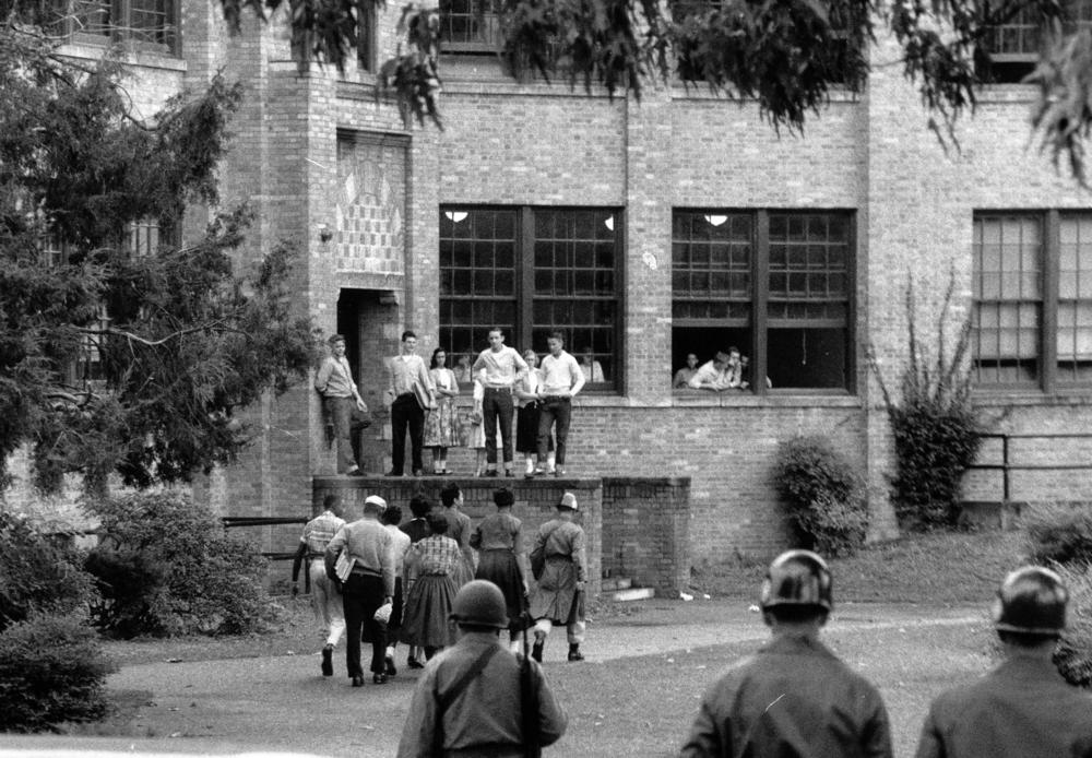In this photo from Oct. 15, 1957, seven of nine Black students walk onto the campus of Central High School in Little Rock, Ark., with a National Guard officer as an escort and as other troops watch.