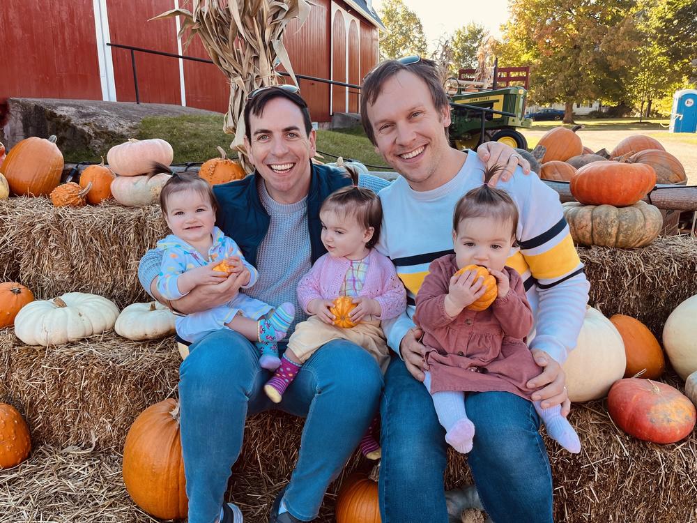 Kevin O'Neill and Eric Portenga with their identical triplet daughters in Oct. 2022. Michigan Governor Gretchen Whitmer signed legislation Monday repealing the state's criminal ban on surrogacy.