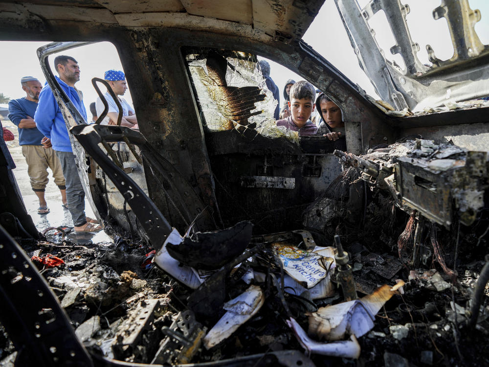 Gaza residents inspect the vehicle where World Central Kitchen workers were killed near the town of Deir al-Balah on Monday. World Central Kitchen, an aid group, says an Israeli airstrike killed at least seven people, including several foreigners.