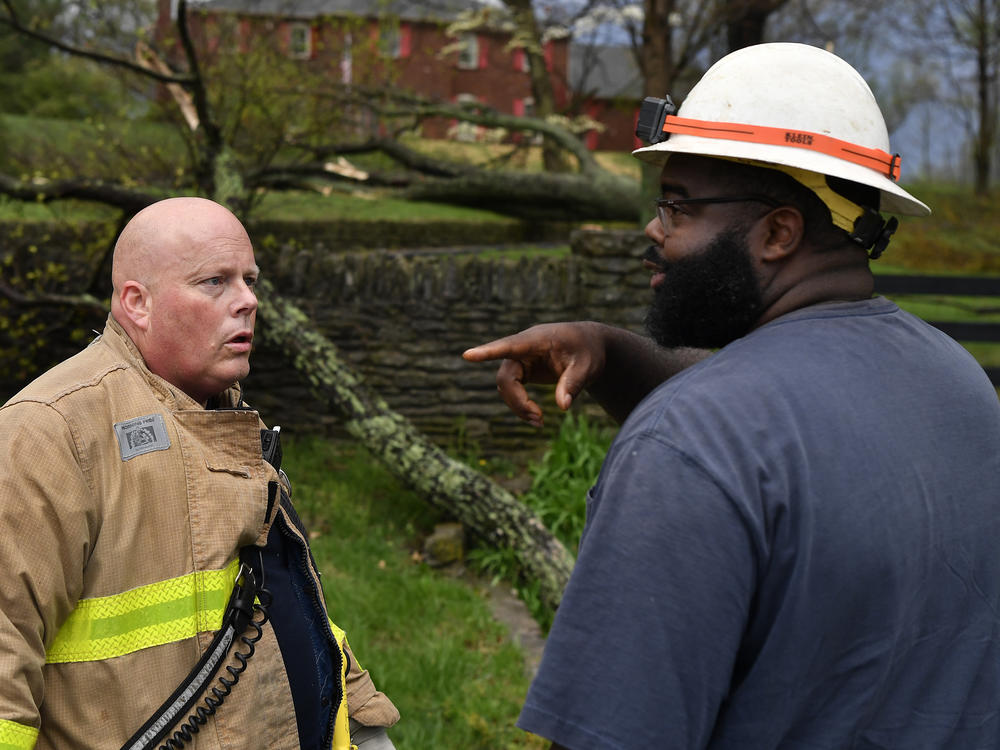 Capt. Patrick Staudenheimer, left, with the Anchorage Middletown Fire Department, speaks with an employee of the Louisville Gas and Electric company informing him of possible gas leaks following severe storms in Prospect, Ky., Tuesday, April 2, 2024.