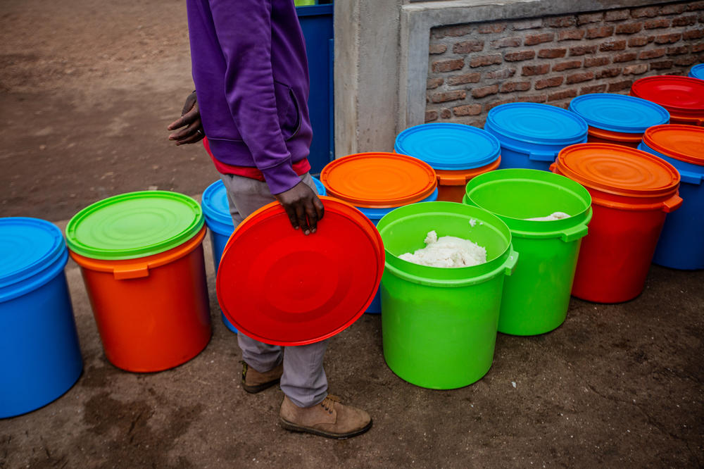 Kitchen workers fill dozens of brightly colored plastic buckets full of warm rice and maize at the Nkamira Transit Center.
