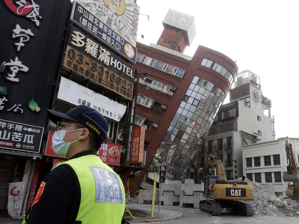 A police officer stands guard near a partially collapsed building a day after a powerful earthquake struck in Hualien City, eastern Taiwan, Thursday, April 4, 2024.