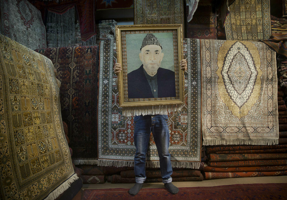 An Afghan carpet seller holds up a framed carpet in his store depicting Hamid Karzai in Kabul, Afghanistan, March 30, 2014.