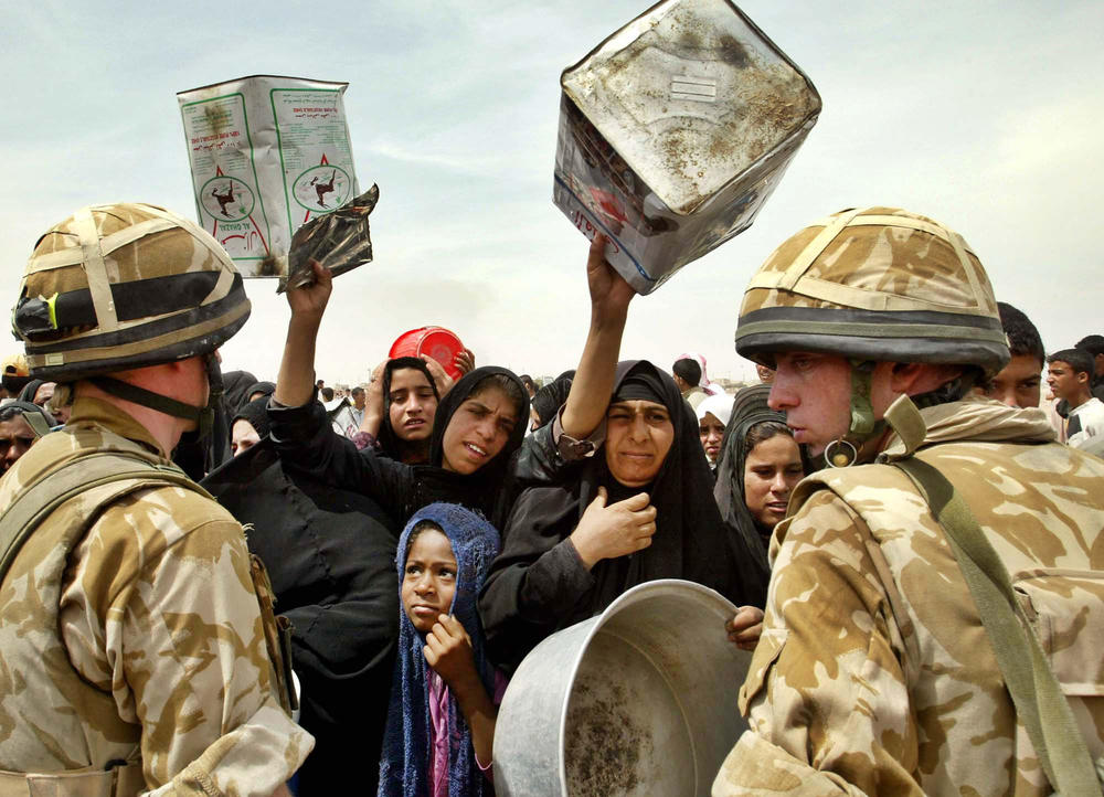 Iraqi women reach out with empty water containers as British soldiers arrive to supply the outskirts of Iraq's southern city of Basra with drinking water, April 4, 2003.