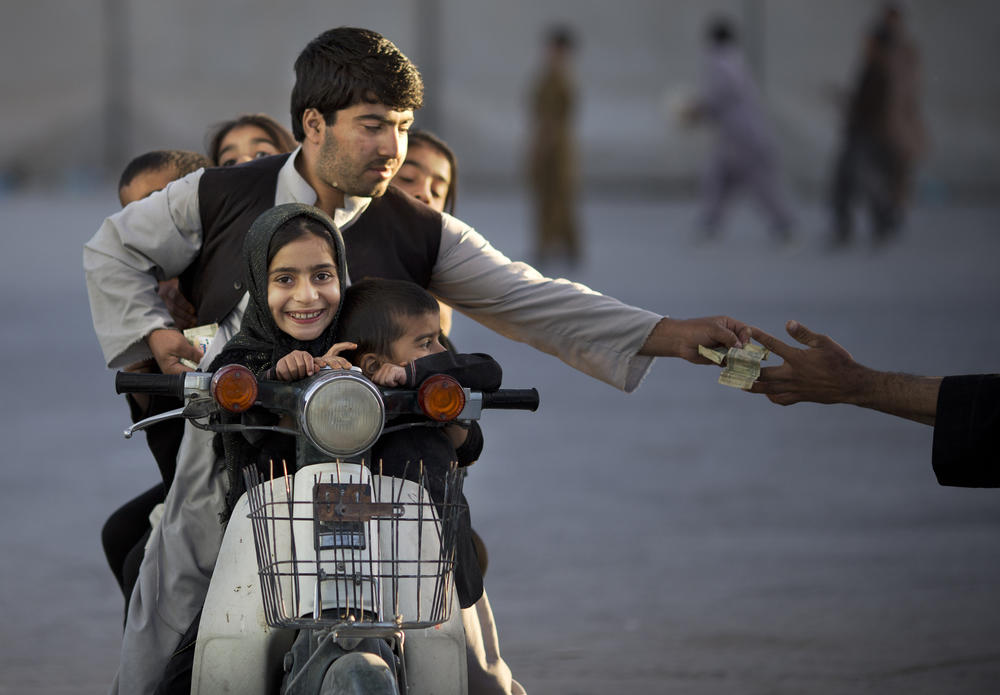 An Afghan man with his five children on his motorbike pays money to enter a park in Kandahar, southern Afghanistan, Nov. 1, 2013.