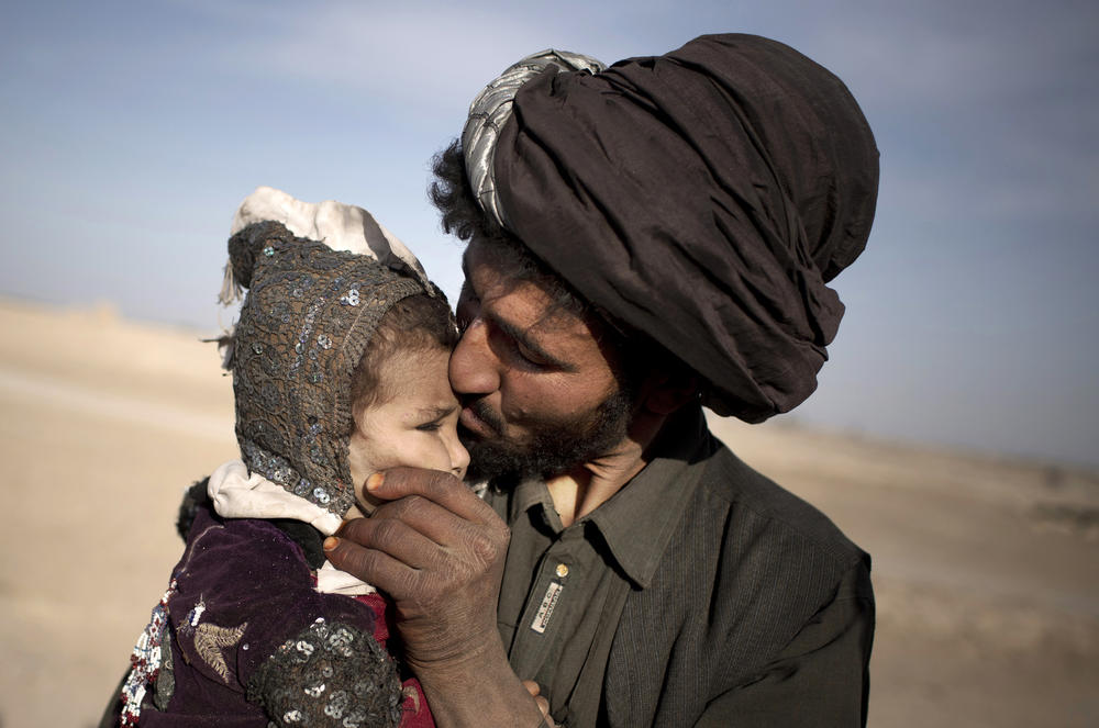 A nomad kisses his young daughter while watching his herd in Marjah, Helmand province, Afghanistan, Oct. 20, 2012.