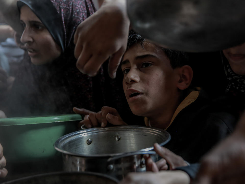 A Palestinian boy holds his bowl in a group of people awaiting food at a soup kitchen in Beit Lahia, Gaza Strip, Feb. 26.