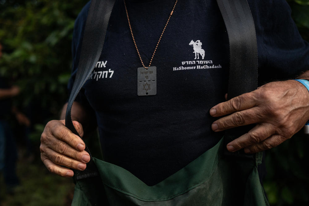 A volunteer wears a dog-tag style necklace with the Hebrew phrase 