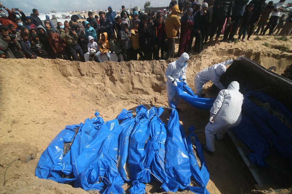 Palestinian workers bury bodies at a grave for victims killed in the Hamas-Israel conflict in the southern Gaza Strip city of Rafah, on March 7.