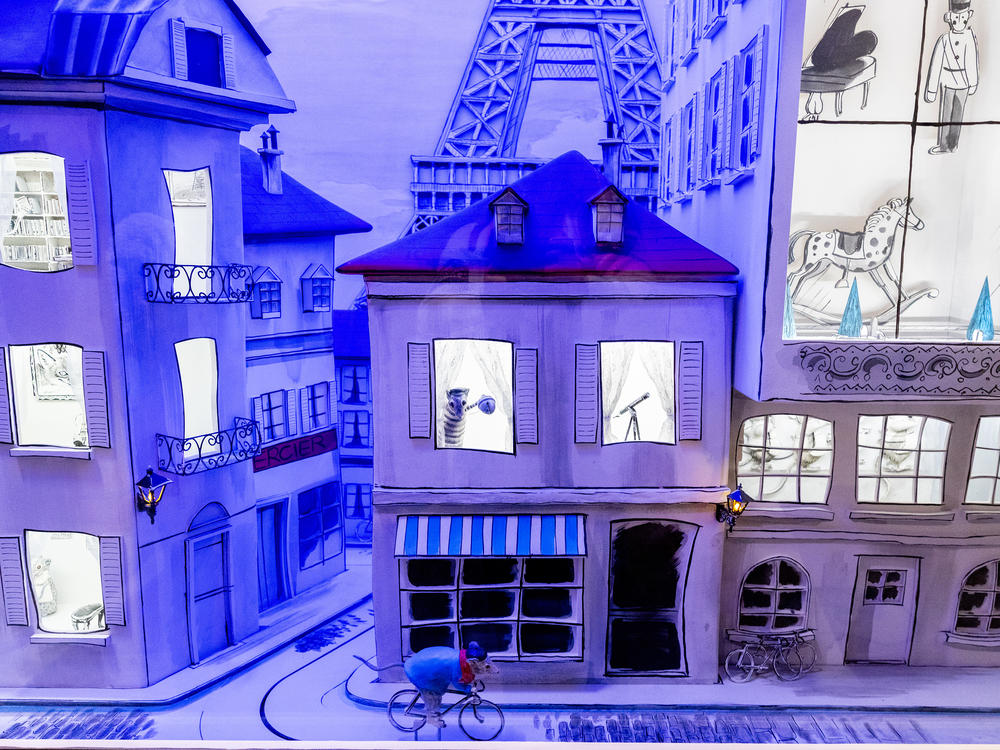 A mouse on a bike from the book <em>Anatole</em>, by Eve Titus, rides around a display of Paris.