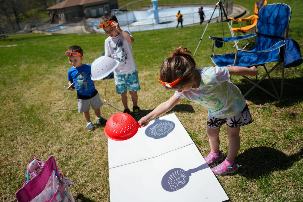Maeve Beebe (right), 4, of Auburn, Mich., makes crescent-shaped shadows with a colander alongside her cousin, Gavin Stodolak (far left), 3, of South Lyon, Mich., and her brother, Everett, 7, at Cole Memorial Park in Chester, Ill.