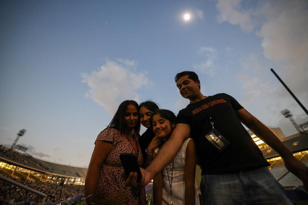 Mindy and Jas Gill take photos with daughter Jaclyn, 15, and Jasmine, 10 during the totality during the eclipse event at Cotton Bowl stadium in Dallas.