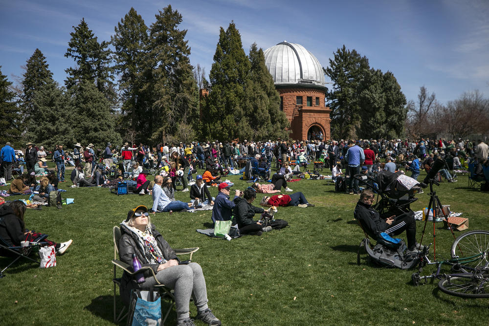 Eclipse watchers fill the lawn at Observatory Park, near the University of Denver, as the sun is partially blocked by the moon.