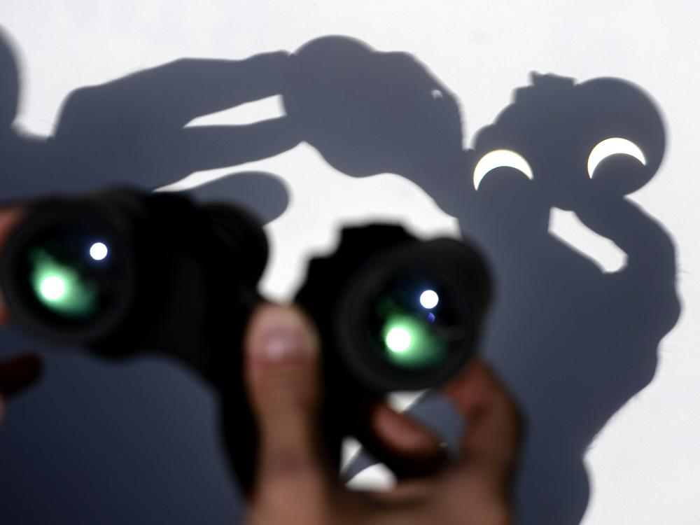 A person uses a pair of binoculars to watch the moon pass infront of the Earth's star marking a total eclipse in Vigo, northwestern Spain on March 20, 2015.