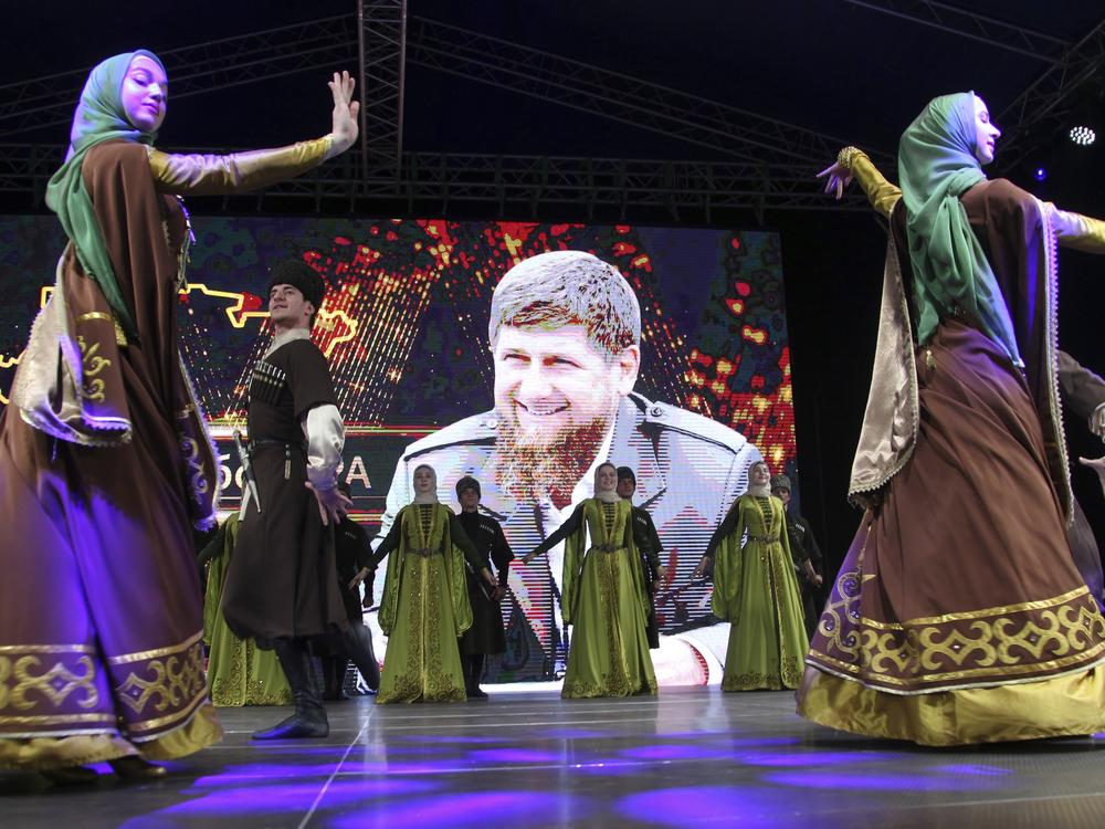Dancers wearing Chechen national costumes perform to celebrate the reelection of Chechnya's regional leader Ramzan Kadyrov (pictured in the background) in Grozny, Russia in September 2021.
