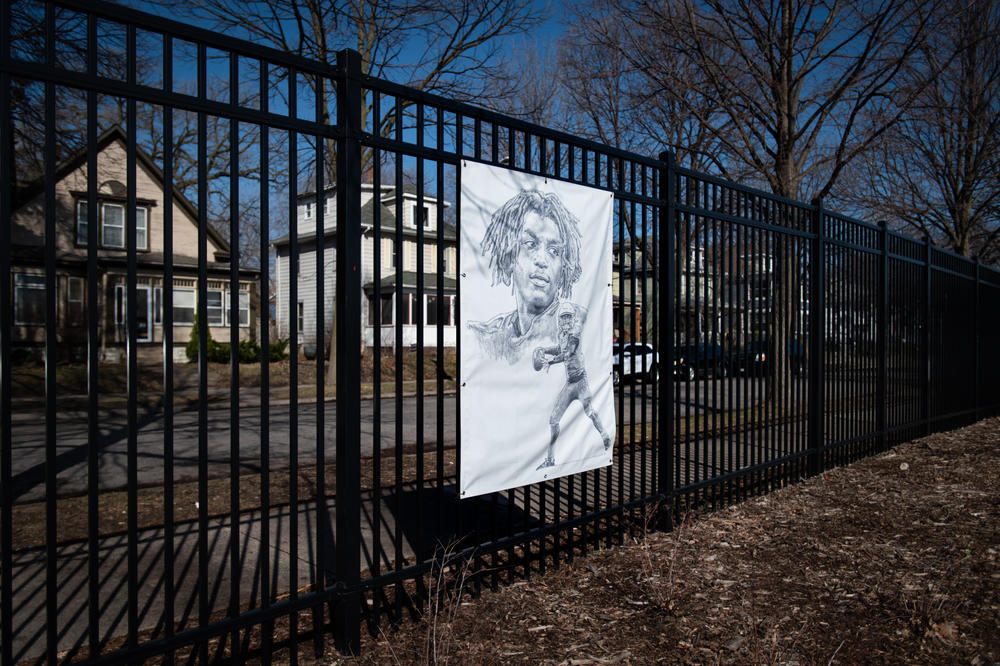 A portrait of Deshaun Hill Jr. hangs outside on the fence surrounding the North Community High School track and football field in Minneapolis.