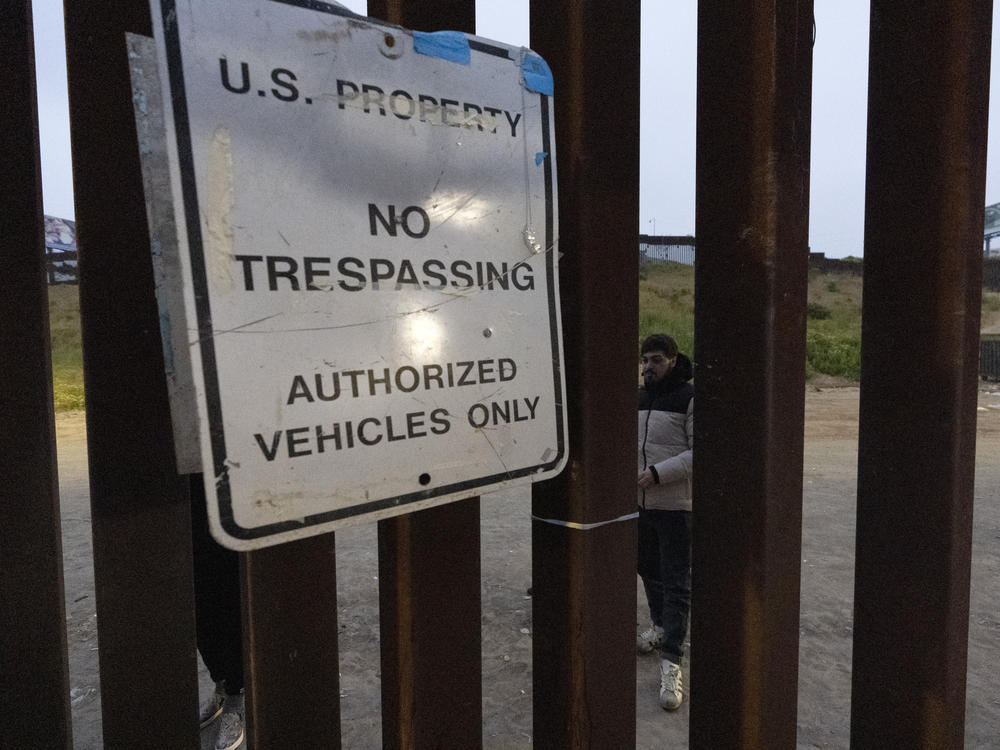 Migrants wait between border walls separating Tijuana, Mexico, and San Diego, to apply for asylum with U.S. authorities on Friday.